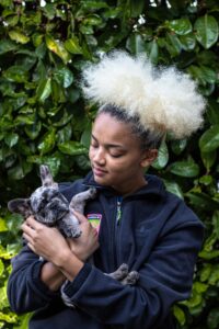 Person with amazing hair holds brindle French bulldog puppy